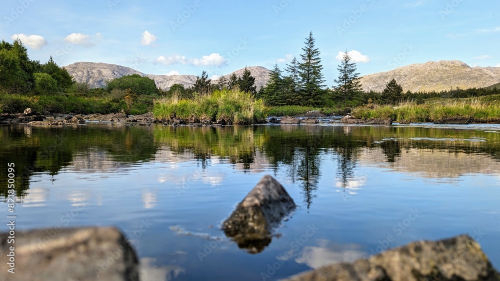 Obraz premium Beautiful landscape scenery, river with mountains and pine trees reflection, nature background Derryclare natural reserve at Connemara national park, county Galway, Ireland, wallpaper