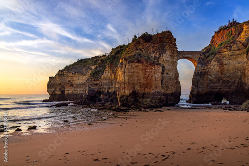 Sunrise at Pinhao Fort Bridge, an ancient stone bridge at Praia dos Estudantes Beach, Lagos, Algarve, Portugal	