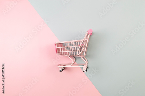 Top view of pink shopping trolley on colorful background. Creative shopping wallpaper, sale. Copy space, flat lay.