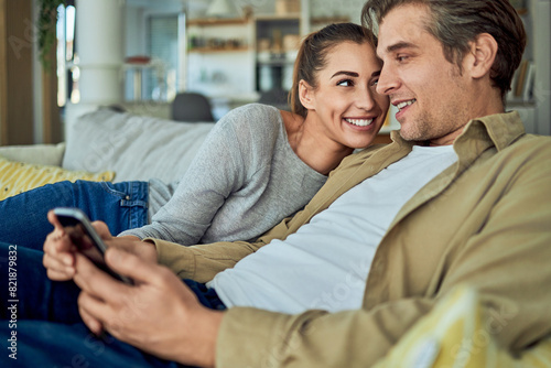 A happy girlfriend snuggling against her boyfriend on the couch to get his attention