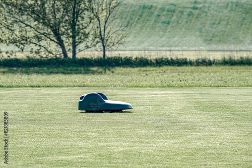 A battery-powered electric lawnmower drives across the field and cuts the grass.