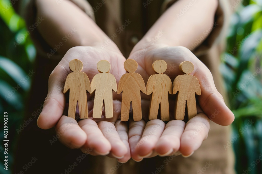 Teamwork and leadership concept symbolized by hands holding wooden figures of people Teamwork and leadership concept symbolized by hands holding wooden figures of people