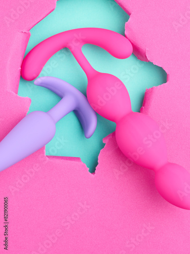 pink sex toys over hole in pink paper background © Nik_Merkulov