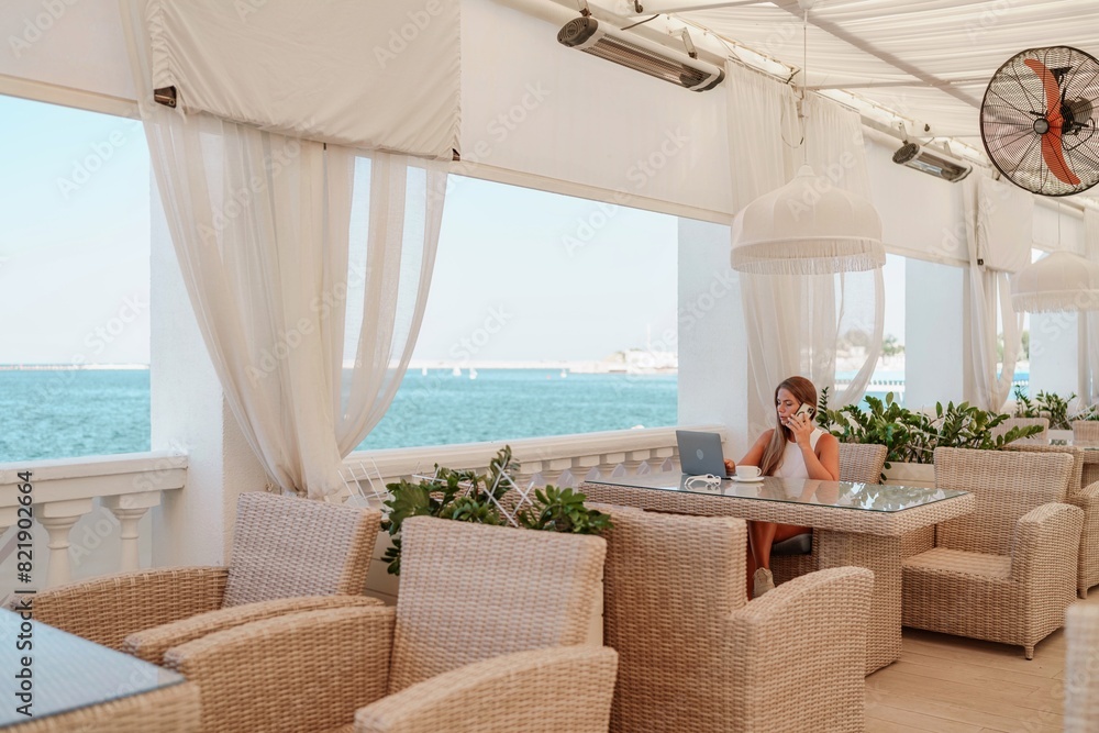 Woman coffee cafe laptop sea. Female freelancer using laptop on coffee break in modern cafe with sea view in the morning Woman coffee cafe laptop sea. Female freelancer using laptop on coffee break in modern cafe with sea view in the morning