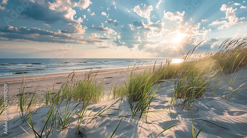 Sunset on sandy beach with dunes and grass, waves and cloudy sky © marcia47