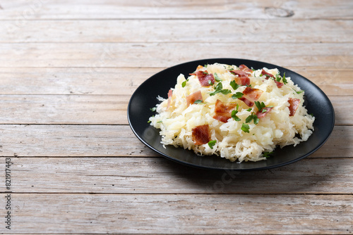 Slovak potato dumplings halusky with steamed sauerkraut and bacon on wooden table. Copy space photo