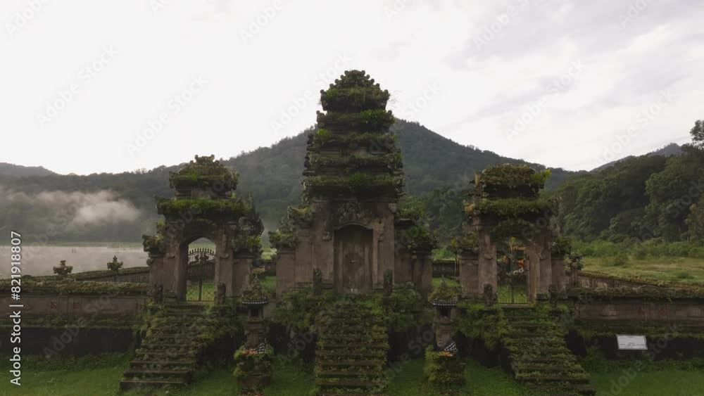 Aerial view of misty Munduk at sunrise with Pura Ulun Danu Tamblingan Temple and serene Tamblingan Lake, Bali, Indonesia.