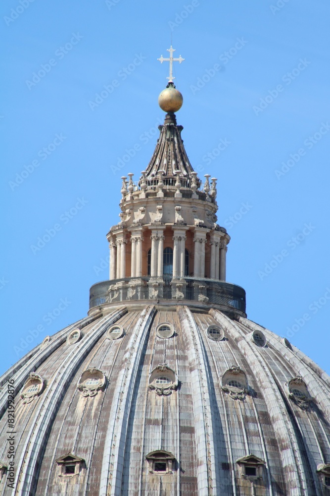 Large domed roof with a white cross placed at the top against a blue sky Large domed roof with a white cross placed at the top against a blue sky
