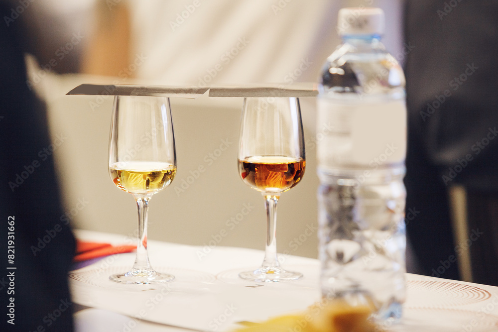 Obraz premium Two Glasses with Covered Degustation Cards of Various types of Whiskey on Table, Close-up.