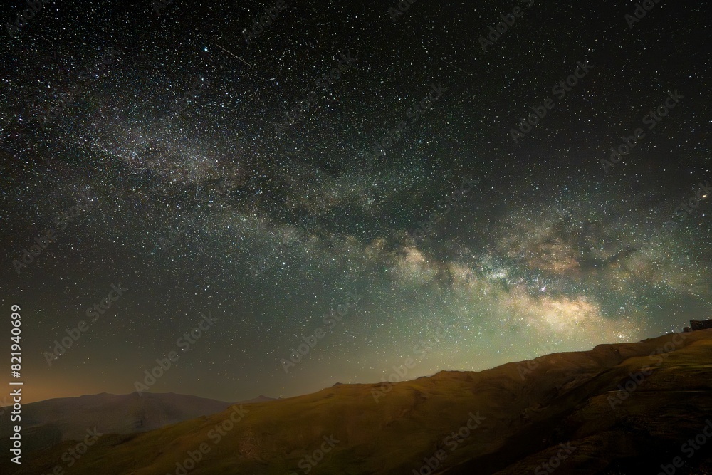 Starlit sky over a mountainous landscape illuminated by a brilliant night sky Starlit sky over a mountainous landscape illuminated by a brilliant night sky