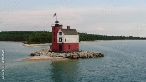 Drone rotating view over lighthouse with USA flag near Mackinac island at sunset