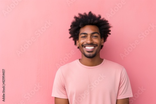 Portrait of a happy afro-american man in his 20s smiling at the camera in front of solid pastel color wall © Markus Schröder