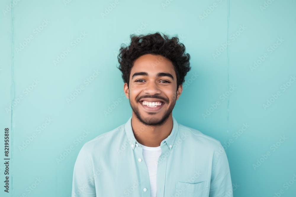 Portrait of a smiling indian man in his 20s smiling at the camera isolated in solid pastel color wall Portrait of a smiling indian man in his 20s smiling at the camera isolated in solid pastel color wall