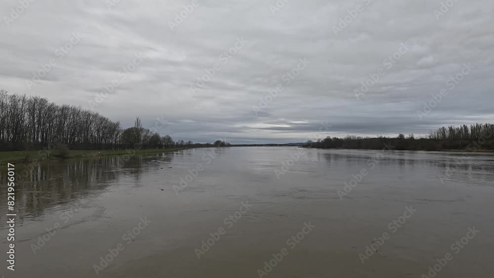 Beautiful shot of a river with leafless trees on its both banks on a cloudy day Beautiful shot of a river with leafless trees on its both banks on a cloudy day