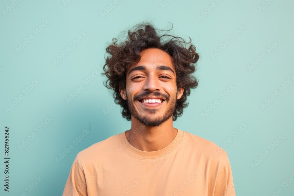 Portrait of a smiling indian man in his 20s smiling at the camera on solid pastel color wall Portrait of a smiling indian man in his 20s smiling at the camera on solid pastel color wall
