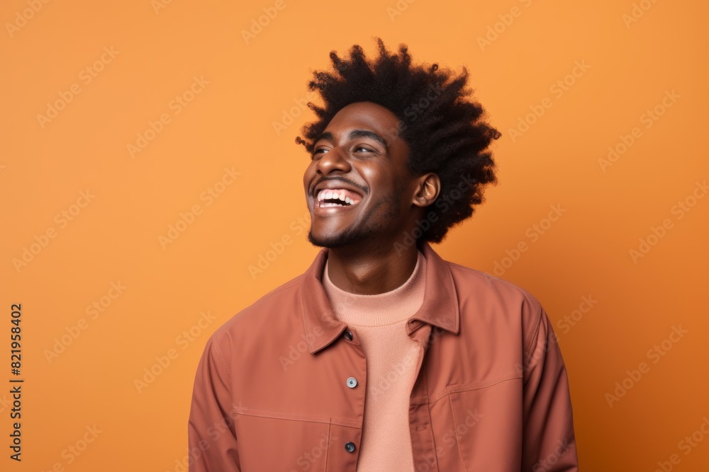 Portrait of a smiling afro-american man in his 20s laughing on solid pastel color wall Portrait of a smiling afro-american man in his 20s laughing on solid pastel color wall