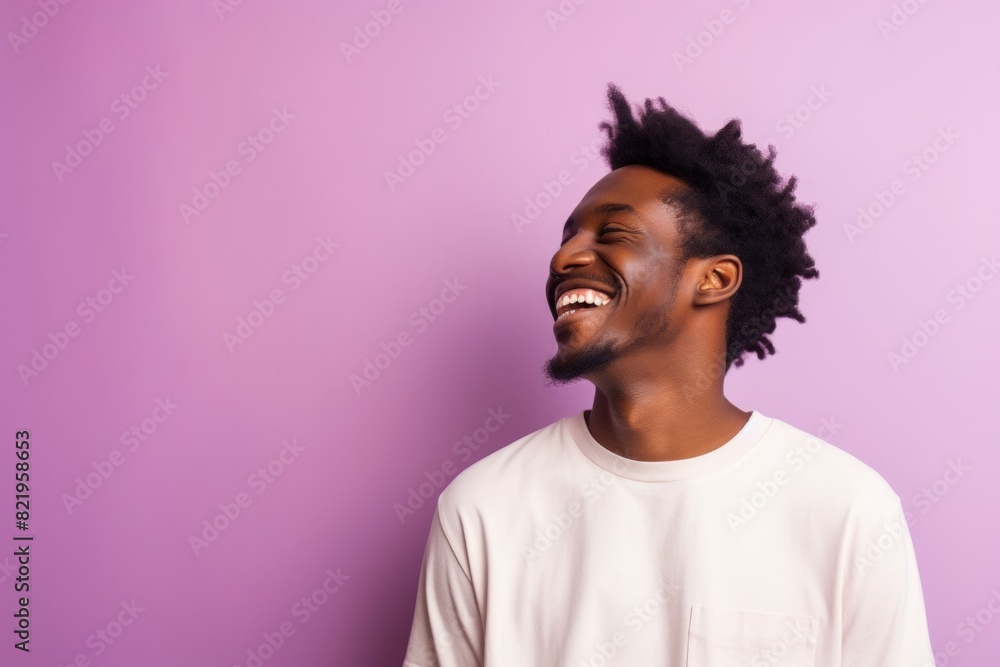 Portrait of a smiling afro-american man in his 20s laughing on solid pastel color wall Portrait of a smiling afro-american man in his 20s laughing on solid pastel color wall