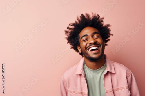 Portrait of a smiling afro-american man in his 20s laughing isolated in solid pastel color wall