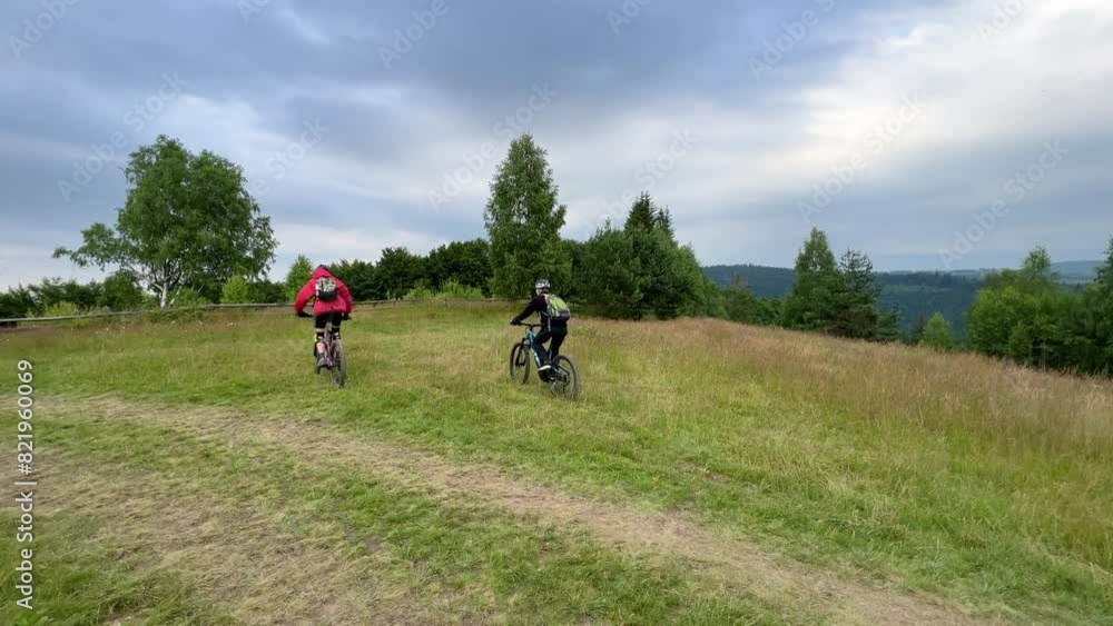 Two cyclists men riding electric bikes outdoors. Male tourists biking in the mountains, wearing helmets and backpacks. Concept of sport, active leisure and nature. Two cyclists men riding electric bikes outdoors. Male tourists biking in the mountains, wearing helmets and backpacks. Concept of sport, active leisure and nature.