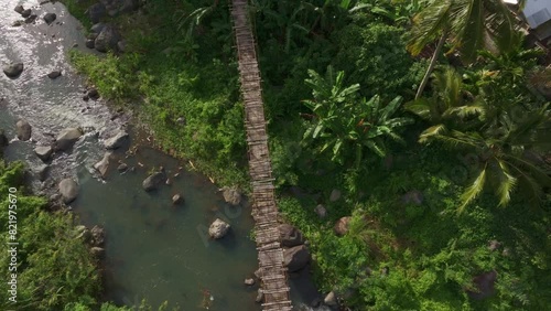 Aerial view of lush greenery with suspension bridge, river, palm trees, and forest, Wologai, Flores, Indonesia. photo