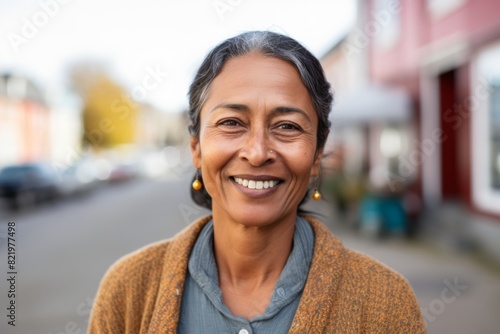 Portrait of a glad indian woman in her 50s smiling at the camera in scandinavian-style interior background