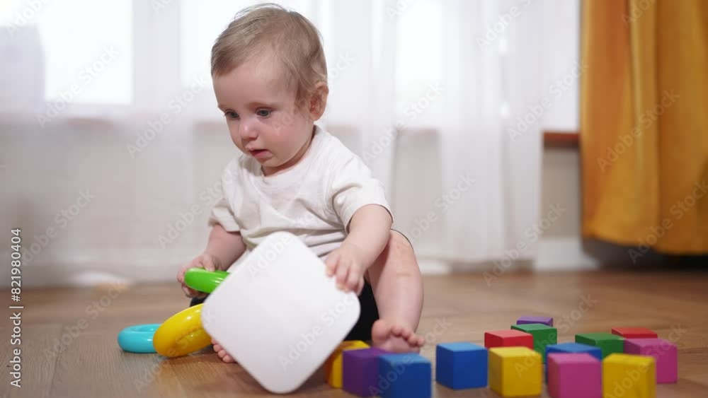 small child is playing. happy childhood dream concept for a little child. cute little child in a white t-shirt plays with different colorful toys while sitting on the floor lifestyle small child is playing. happy childhood dream concept for a little child. cute little child in a white t-shirt plays with different colorful toys while sitting on the floor lifestyle