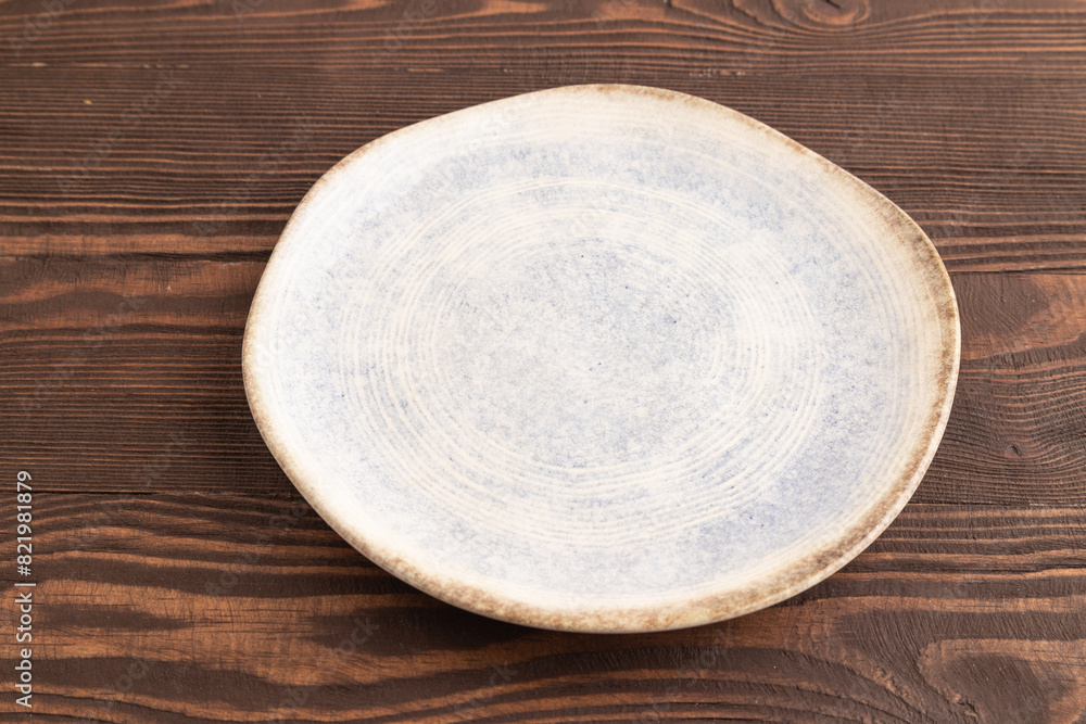 Empty blue and white ceramic plate on brown wooden. Side view, copy space Empty blue and white ceramic plate on brown wooden. Side view, copy space