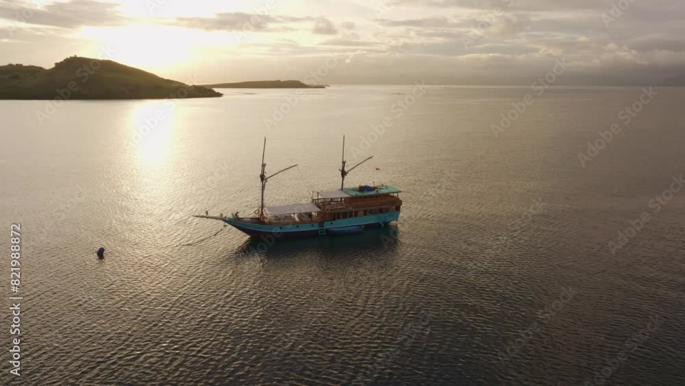 Aerial view of serene sunrise over anchored boat in Flores Sea, Indonesia. Aerial view of serene sunrise over anchored boat in Flores Sea, Indonesia.