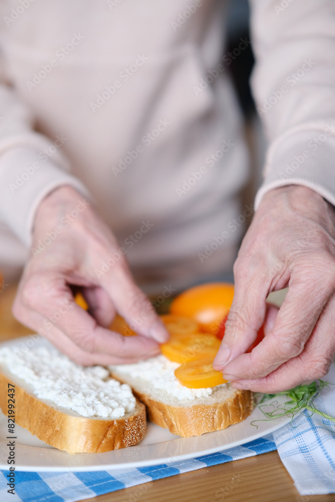 Age woman preparing healthy sandwiches with microgreens and vegetables Age woman preparing healthy sandwiches with microgreens and vegetables