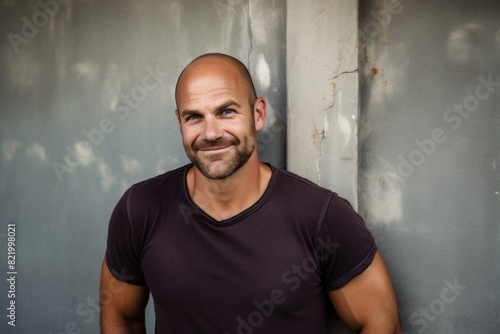 Portrait of a grinning man in his 40s smiling at the camera in front of bare concrete or plaster wall © Markus Schröder
