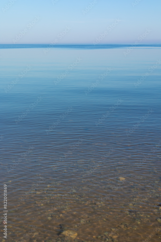 Obraz premium A very calm Baltic sea water surface with reflections of the sun. Beautiful summer scenery of Northern Europe.