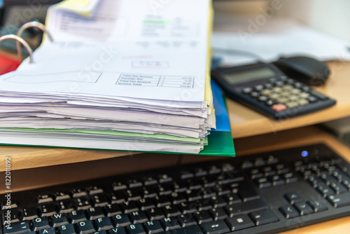 Close up of a business work station with a folder of invoices, calculator, computer keyboard and mouse. Business accounting concept.
