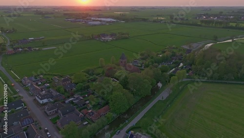 Aerial view of peaceful village with fields and church at sunset, Westerwijtwerd, Groningen, Netherlands. photo