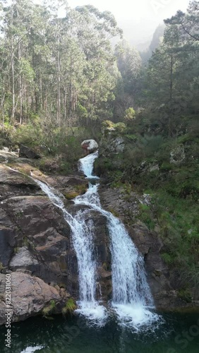 Aerial view of cascading waterfall in lush forest by river, Pozas de Mougas, Pontevedra, Spain. photo