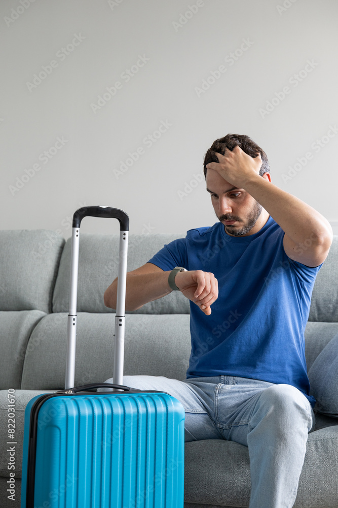 Astonished man looking at the watch together with his travel suitcase. Man worried about the delay of his flight. Man making a scared gesture looking at the time on his watch. man realizes he is late Astonished man looking at the watch together with his travel suitcase. Man worried about the delay of his flight. Man making a scared gesture looking at the time on his watch. man realizes he is late