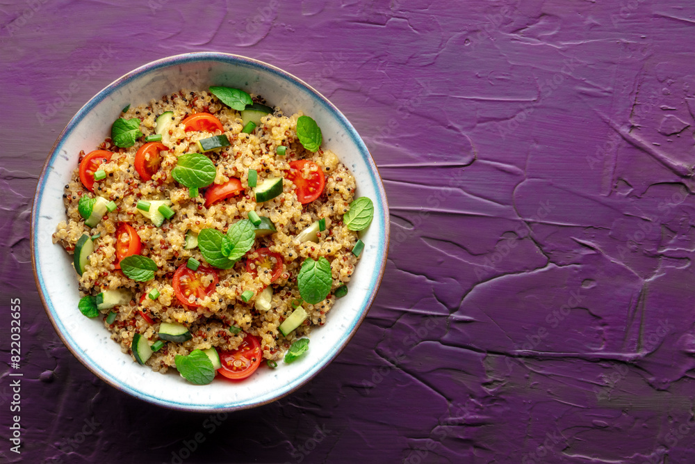 Quinoa tabbouleh salad in a bowl, a healthy dinner with tomatoes and mint, top shot with copy space on a purple background Quinoa tabbouleh salad in a bowl, a healthy dinner with tomatoes and mint, top shot with copy space on a purple background