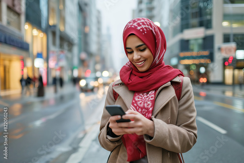 Arab girl looking at her smartphone and smiling in the background of the city