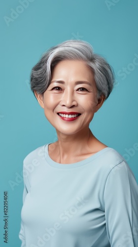 Cyan Background Happy Asian Woman Portrait of Beautiful Older Mid Aged Mature Smiling Woman good mood Isolated Anti-aging Skin Care Face Beauty Product 