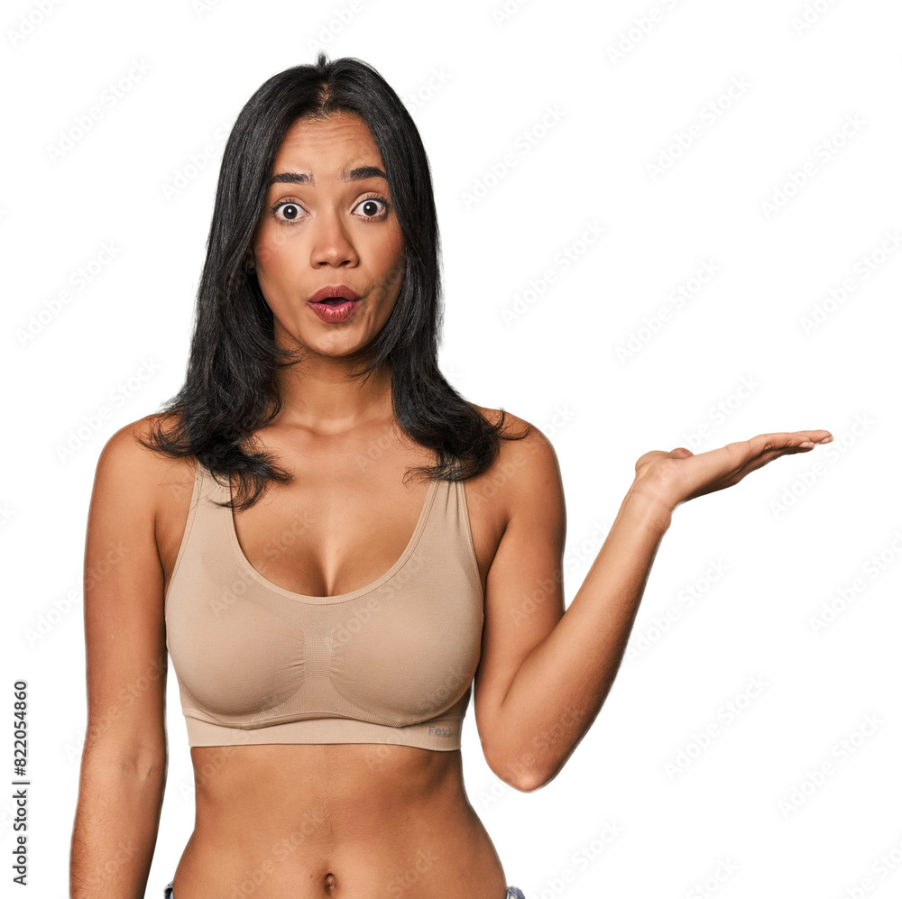 Young Filipino woman in light wear impressed holding copy space on palm. Young Filipino woman in light wear impressed holding copy space on palm.
