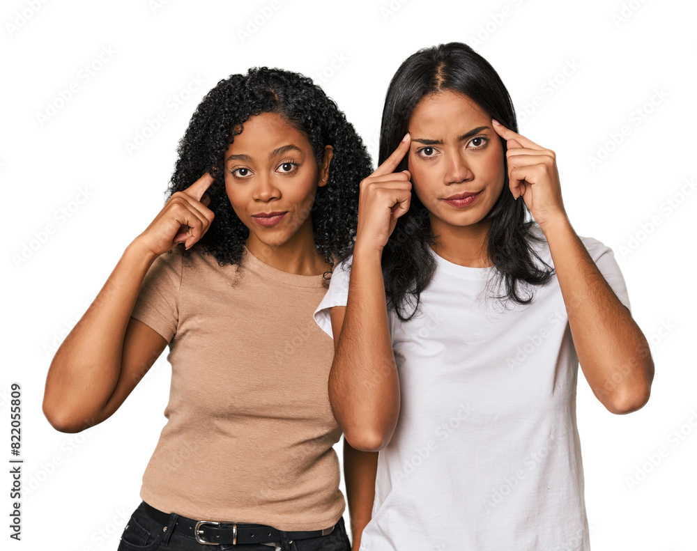 Young Latin friends in studio focused on a task, keeping forefingers pointing head. Young Latin friends in studio focused on a task, keeping forefingers pointing head.