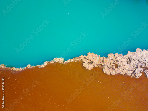 Obraz na płótnie Aerial drone view of polluted river. The aftermath of excessive phosphate release to the river. Turquoise and brown colors. Environmental disaster caused by humans. Ecological concern. w salonie