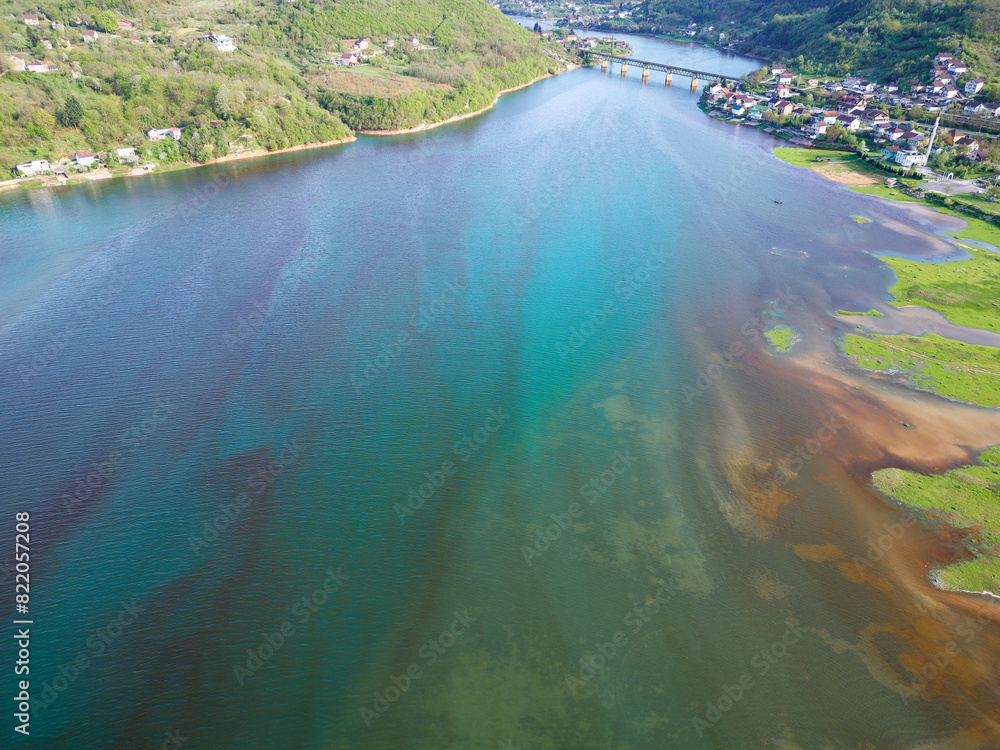 Aerial drone view of polluted river. The aftermath of excessive phosphate release to the river. Turquoise and brown colors. Environmental disaster caused by humans. Ecological concern.