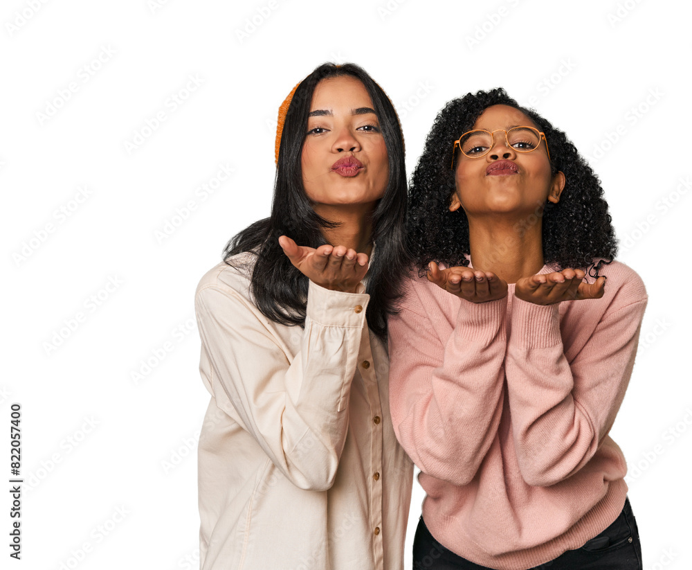 Young Latin friends together in studio folding lips and holding palms to send air kiss. Young Latin friends together in studio folding lips and holding palms to send air kiss.