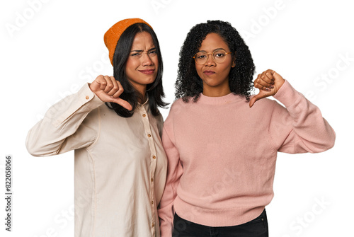 Canvas Print Young Latin friends together in studio showing thumb down, disappointment concept