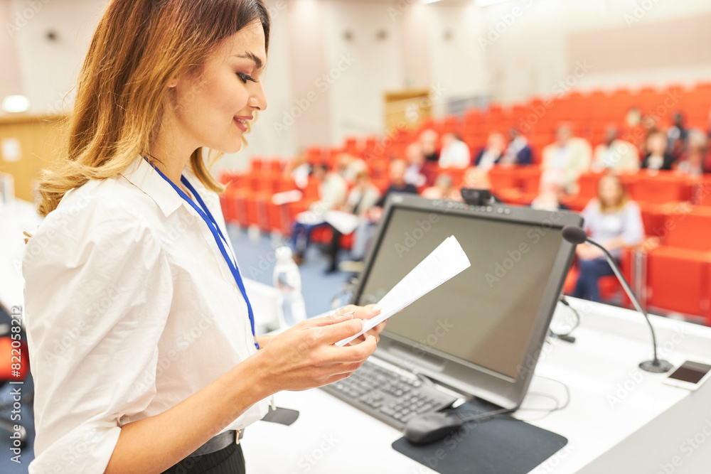 Speaker reading document at business conference in auditorium Speaker reading document at business conference in auditorium