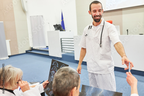 Speaker giving pens to doctors with x-rays at medical conference