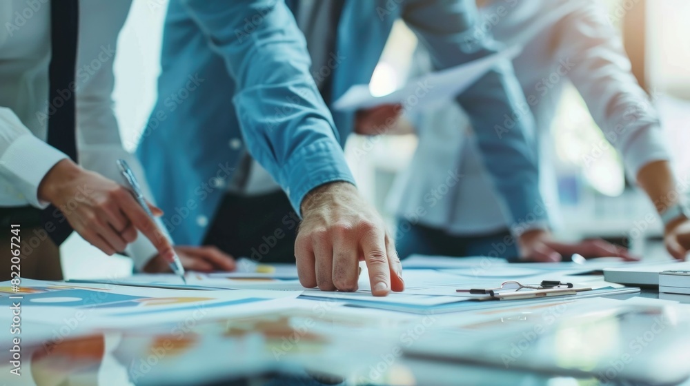 A group of people standing around a table with papers, suitable for business meetings or teamwork concepts A group of people standing around a table with papers, suitable for business meetings or teamwork concepts