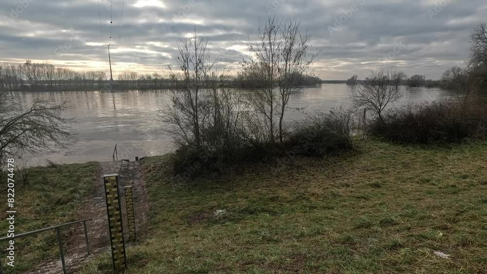 Leafless trees and dry plants on the bank of Danube river with flood water under dark cloudy sky Leafless trees and dry plants on the bank of Danube river with flood water under dark cloudy sky