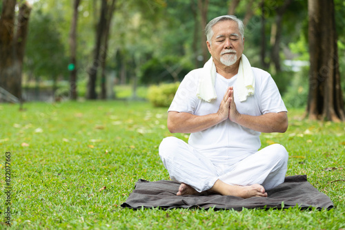asian senior man meditating and doing yoga in the park