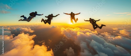 Group of skydivers free falling at sunset above clouds. photo